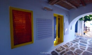Naoussa, Paros, covered walkway with yellow doors and stone paving