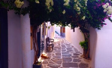 Naoussa, Paros, shaded alley under bougainvillea with a stone path