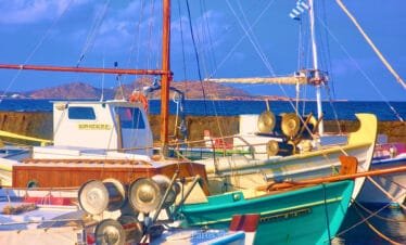 Naoussa, Paros harbor traditional fishing boats tied up with the Greek flag in view