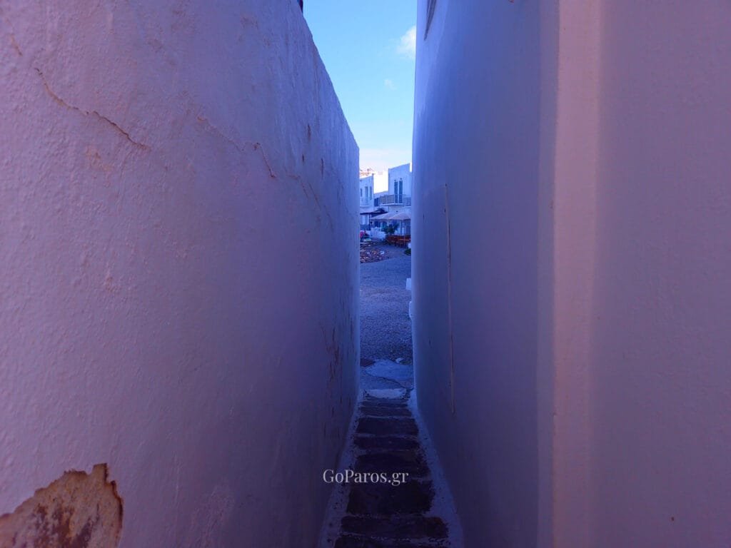 Naoussa, Paros, narrow passage between white walls leading toward a small square