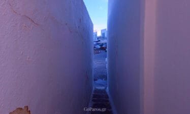 Naoussa, Paros, narrow passage between white walls leading toward a small square