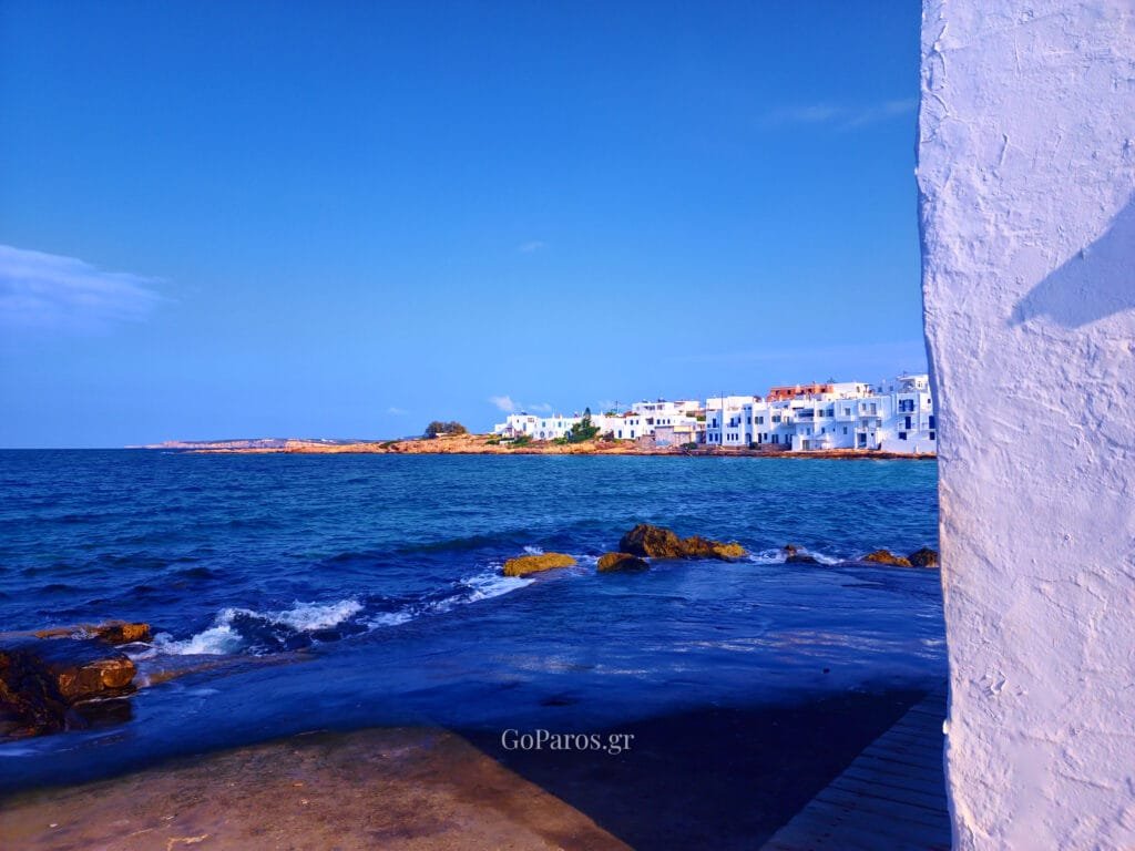 Paros coastline, view of whitewashed houses by the sea and rocky shoreline
