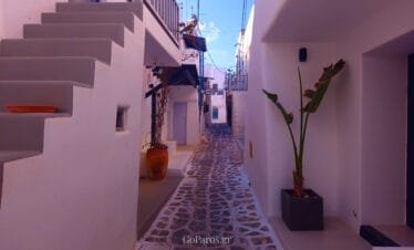 Naoussa, Paros, quiet white alley with stone path, steps, and a potted plant