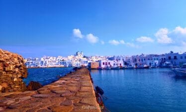 Naoussa, Paros harbor, stone jetty leading into the water with town skyline and boats