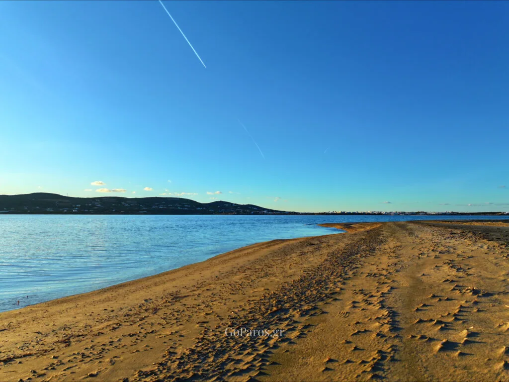 Pounda Beach West, Paros, long sandbar with footprints leading toward the sea at dusk
