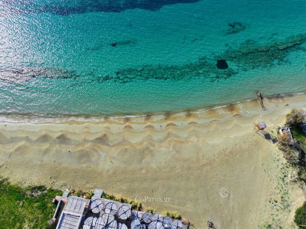 Aerial view of Krios Beach with clear water, reef patterns and sandy shoreline, Paros.