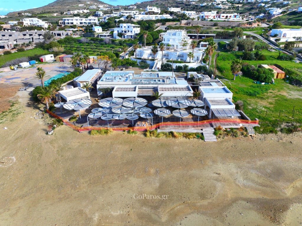 Aerial view of a beachfront beach club with sun umbrellas beside Krios Beach, Paros.