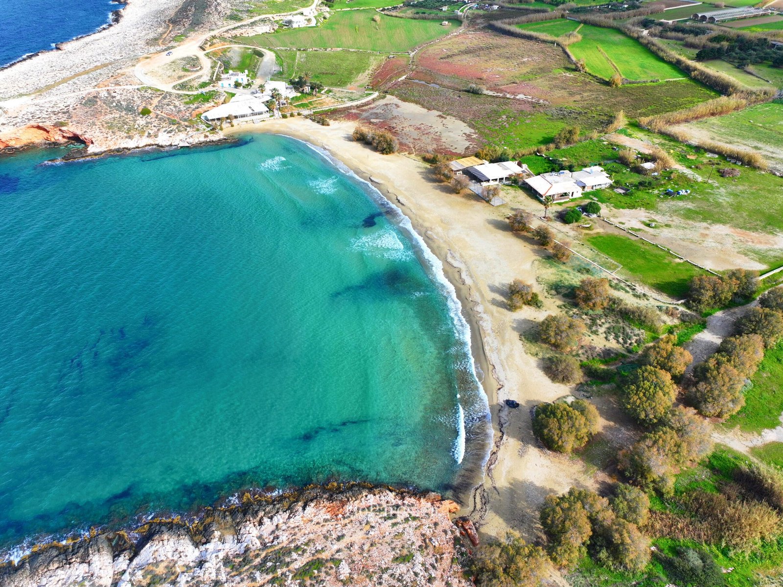 Aerial view of Parasporos Beach showing the coastal curve and clear water, Paros.