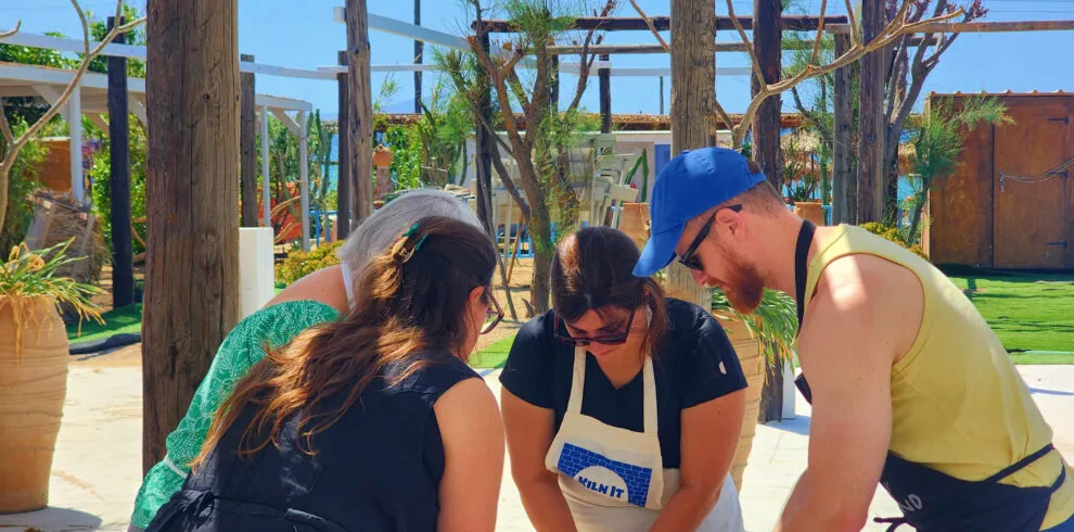 Small group learning clay preparation during a pottery class in Paros