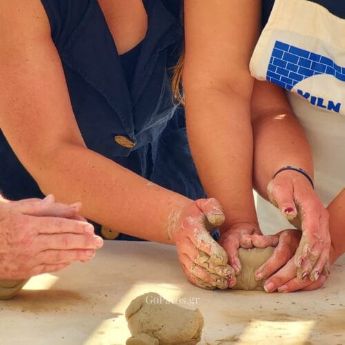 Guests shaping clay by hand during a beginner-friendly pottery workshop in Paros