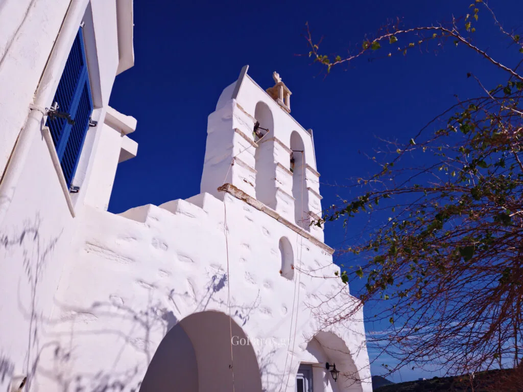 White church bell tower against a deep blue sky in Kostos village, Paros