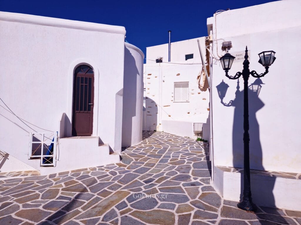 Whitewashed alley with stone paving and a street lamp in Kostos, Paros