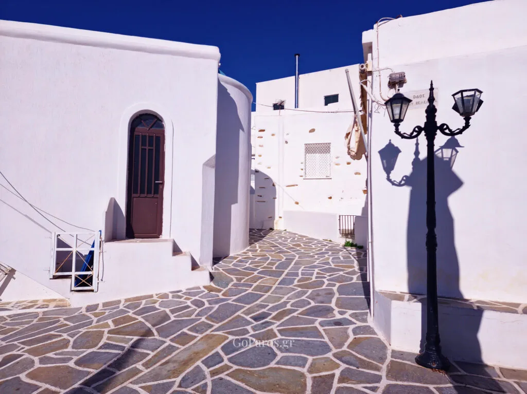 Whitewashed alley with stone paving and a street lamp in Kostos, Paros
