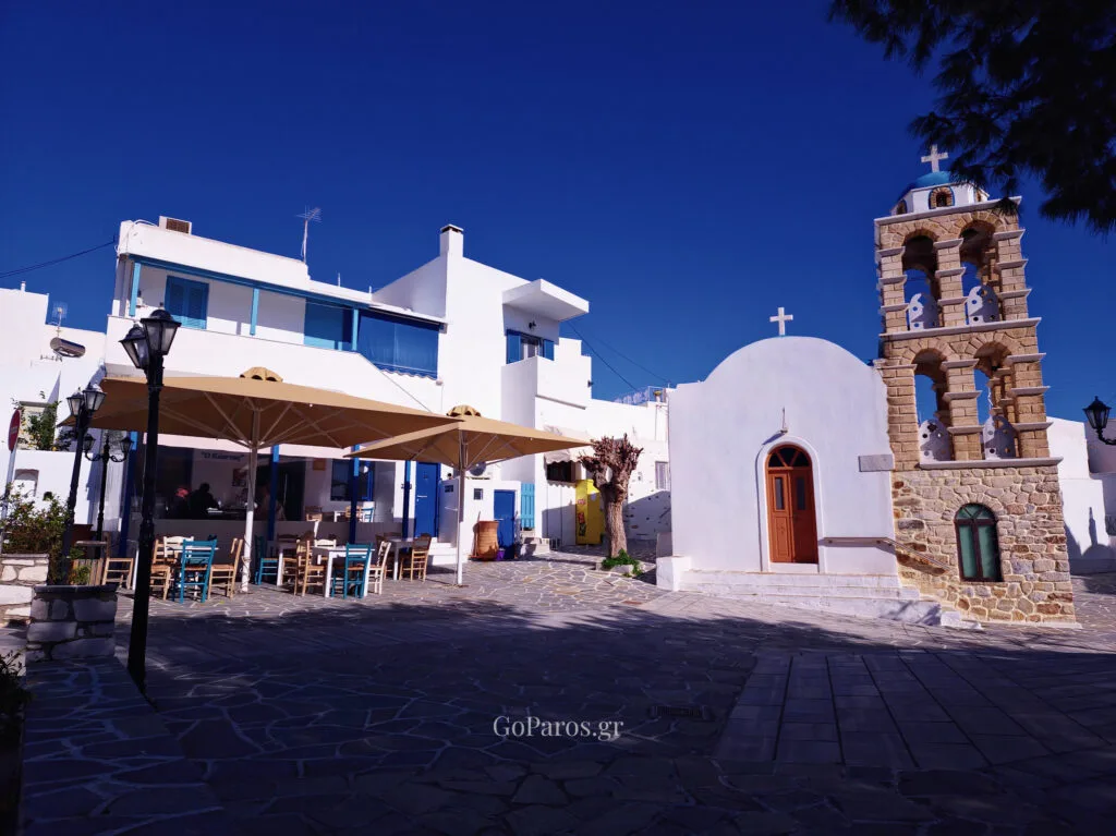 Traditional village square in Kostos, Paros with a white church and stone bell tower