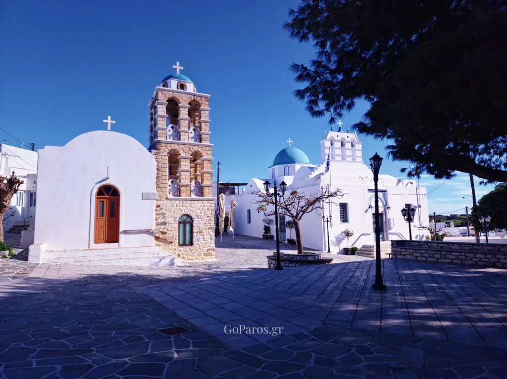 Village square in Kostos, Paros with two white churches and a stone bell tower