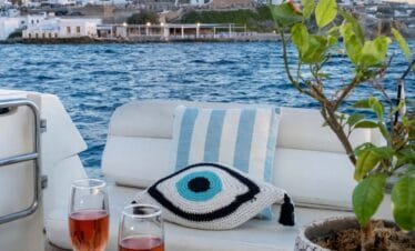 Aft deck drinks with Mykonos windmills view, private yacht cruise from Paros.